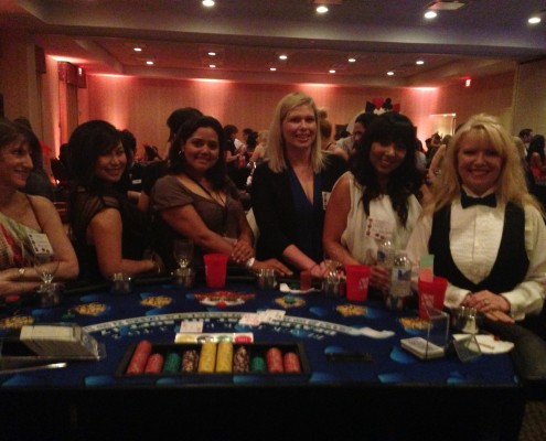 female group posing around card table
